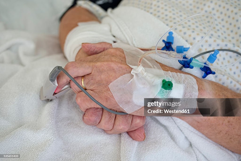 Hands of senior man with cannulae and band-aid being in intensive care