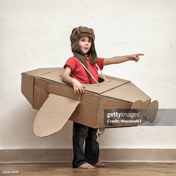 little boy with pilot hat and cardboard box aeroplane showing at something - boy in a box stockfoto's en -beelden