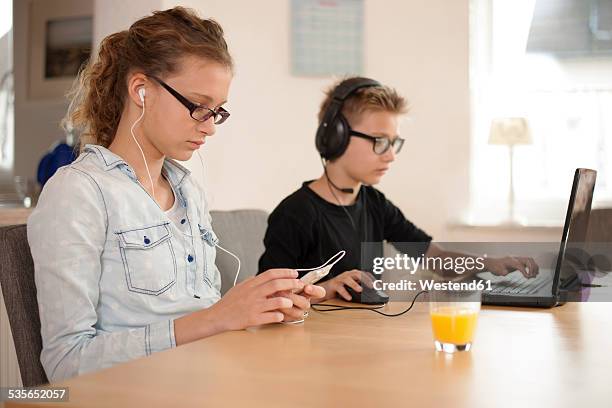 brother and sister with headphones and earphones using laptop and smartphone - mp3 juices 個照片及圖片檔