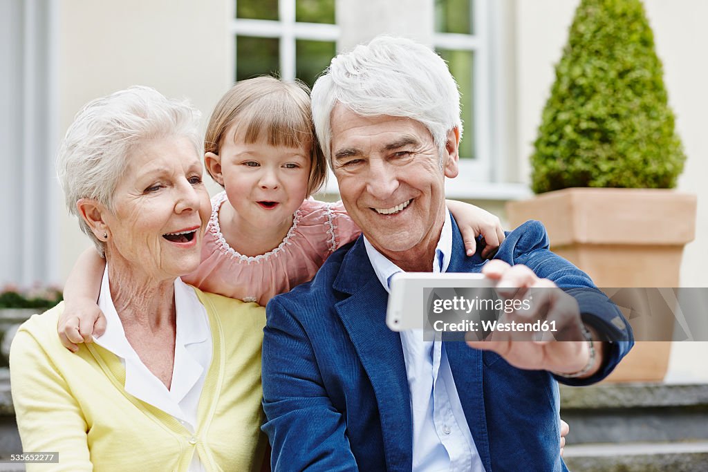 Germany, Hesse, Frankfurt, Senior couple taking selfie with granddaughter