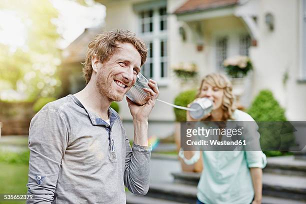 germany, hesse, frankfurt, couple in garden playing with tin can phone - plåtburkstelefon bildbanksfoton och bilder