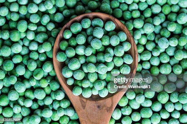 wooden spoon and frozen peas - aliment surgelé photos et images de collection