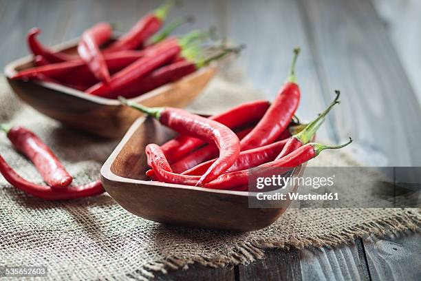 wooden bowl of red chili peppers on jute and wood - chillies stock-fotos und bilder