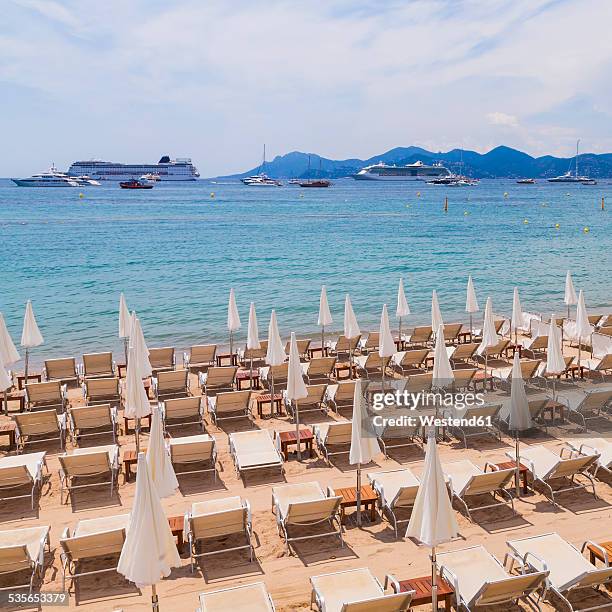 france, cote d'azur, cannes, sun loungers and beach umbrellas on beach - cannes beach stock pictures, royalty-free photos & images