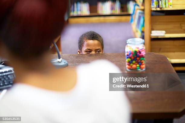 boy in library peeking at candy jar - candy jar stock pictures, royalty-free photos & images