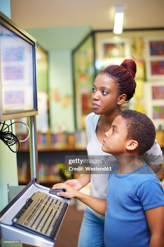 Young woman and boy using computer in library