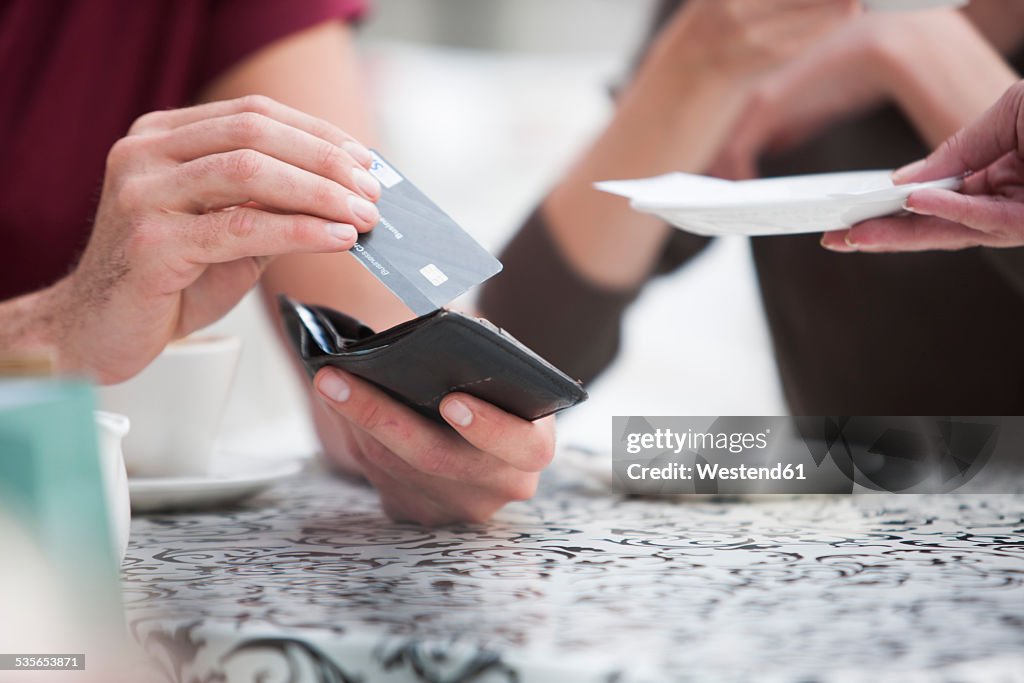 Man paying bill with credit card in a pavement cafe