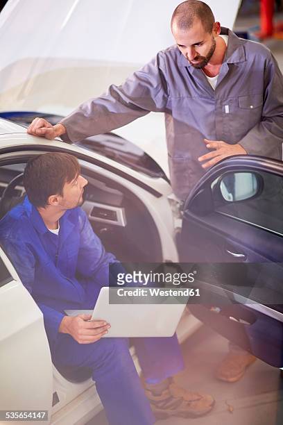 two car mechanics with laptop in repair garage - mechatronics fotografías e imágenes de stock