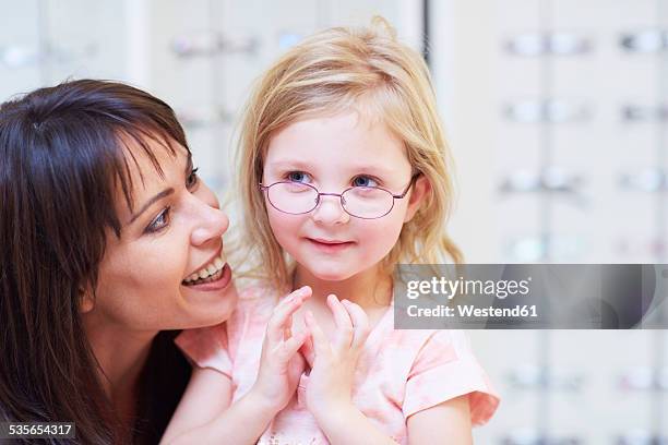 girl at the optician trying on glasses - eye test equipment imagens e fotografias de stock