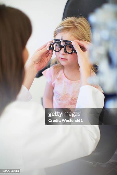 eye doctor examining girl's vision - optical instrument stock pictures, royalty-free photos & images