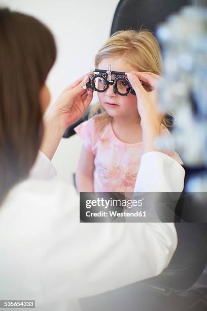 eye doctor examining girl's vision - optical equipment stock pictures, royalty-free photos & images