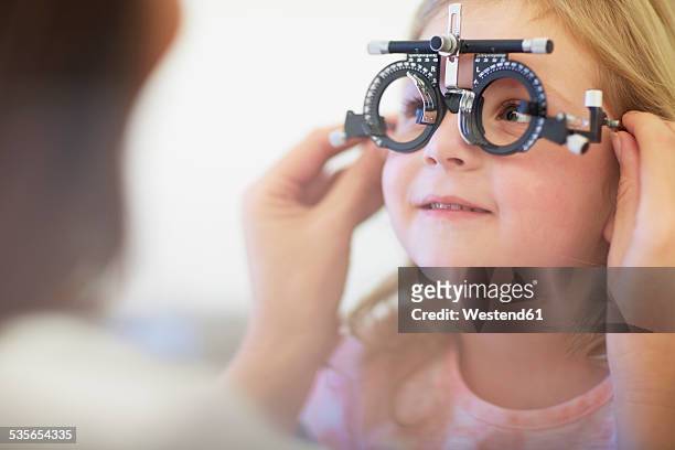 eye doctor examining girl's vision - optometria imagens e fotografias de stock