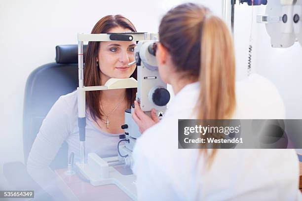 eye doctor examining woman's vision - ophthalmologist stock pictures, royalty-free photos & images
