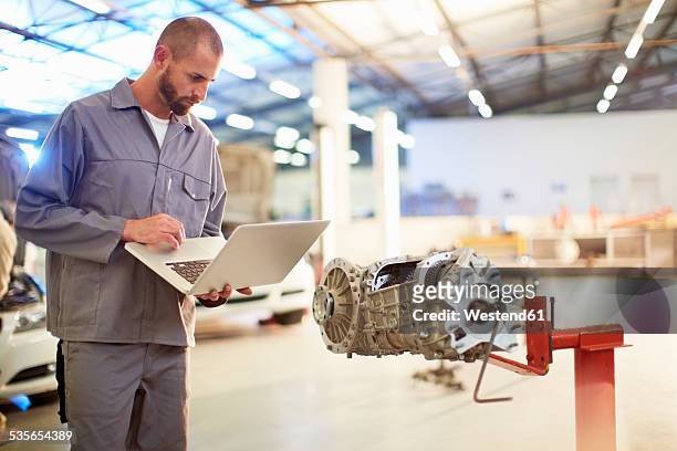 car mechanic using laptop in repair garage - mechatronics fotografías e imágenes de stock
