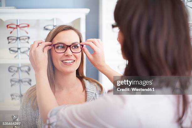 woman at the optician trying on glasses - choosing eyeglasses stock pictures, royalty-free photos & images