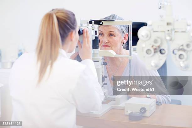 eye doctor examining senior woman's vision - eye exam stock pictures, royalty-free photos & images