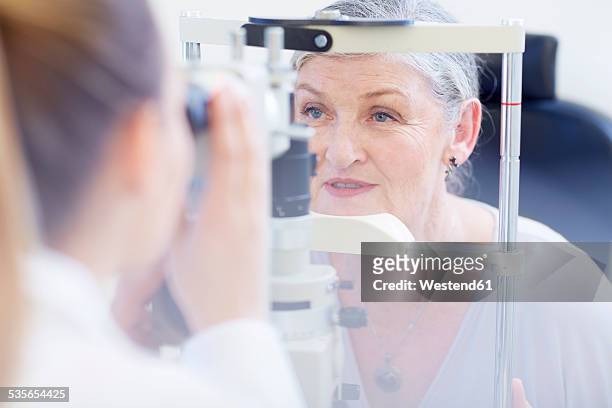eye doctor examining senior woman's vision - eye test equipment imagens e fotografias de stock