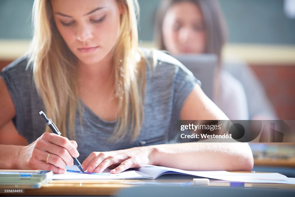 Female student in classroom writing at desk