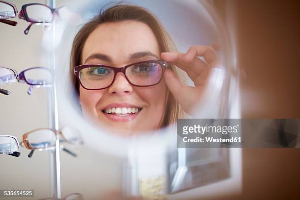 woman at the optician trying on glasses - buying eyeglasses stock pictures, royalty-free photos & images