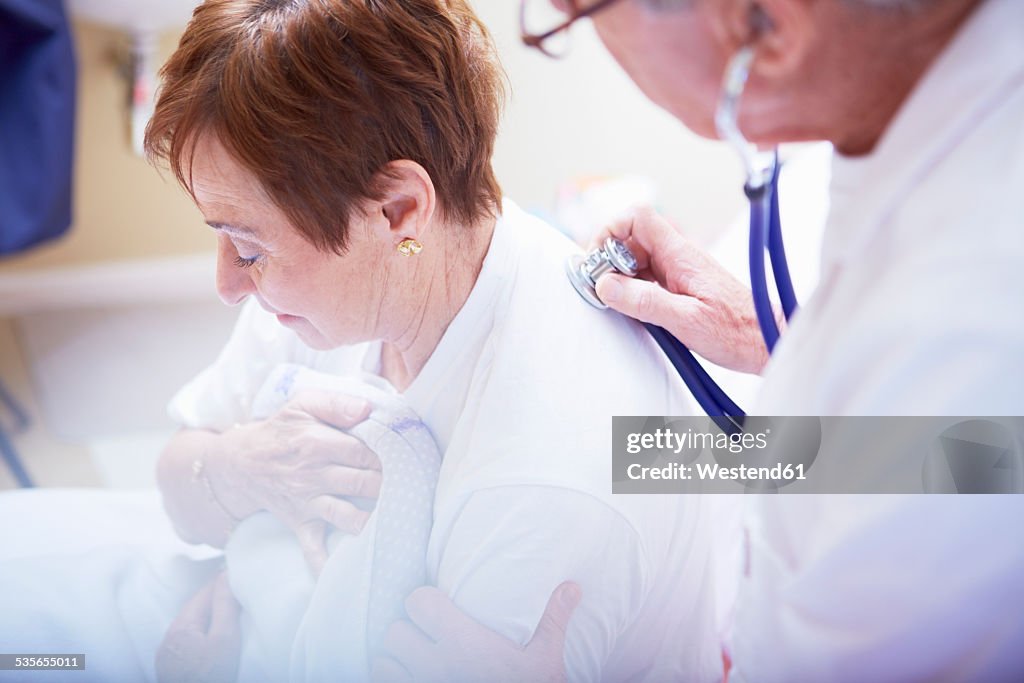 Doctor examining senior woman in hospital bed