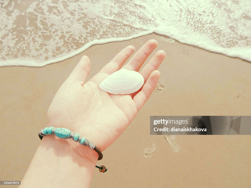 Woman holding seashell in hand