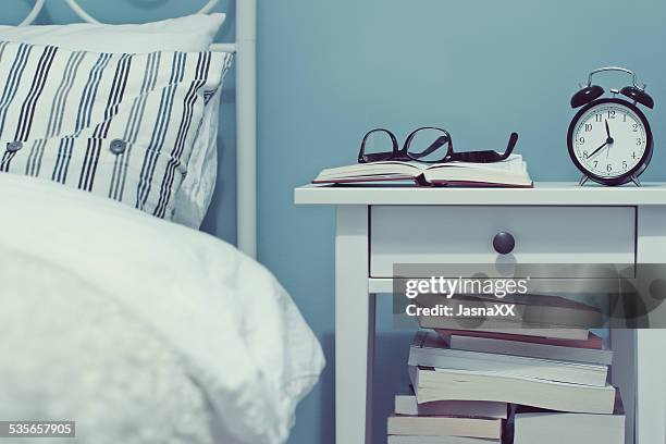 night table with books and alarm clock - bedside table stock pictures, royalty-free photos & images