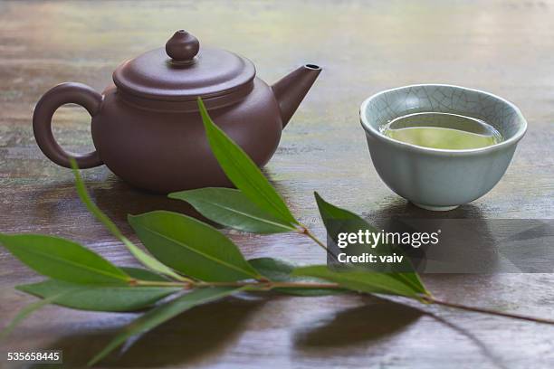 still life with ceramic teapot, cup of green tea, and branch of tea plant - ティーポット ストックフォトと画像