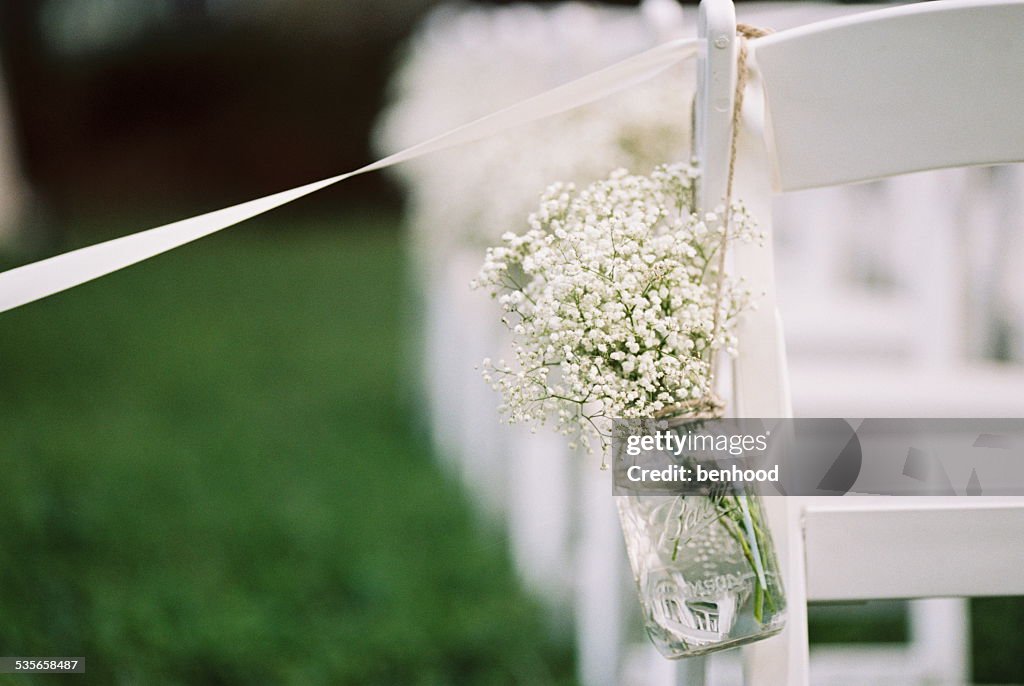USA, Florida, Orange County, Winter Park, Close-up shot of bunch of baby's breath flowers in a mason jar and white ribbon attached to back of white chair