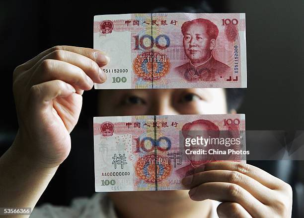 Chinese man identifies a new issued 100 yuan note with an old one issued in 1999, at a bank on August 31, 2005 in Shanghai, China. Authorities issued...