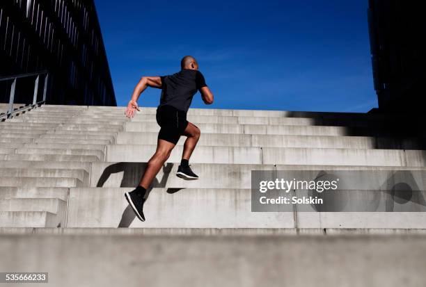 man running up outdoor stairs - stufen stock-fotos und bilder