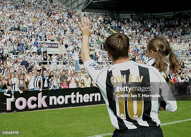 Michael Owen waves to fans as he carries his daughter, Gemma, after signing for Newcastle United at St James' Park on August 31, 2005.