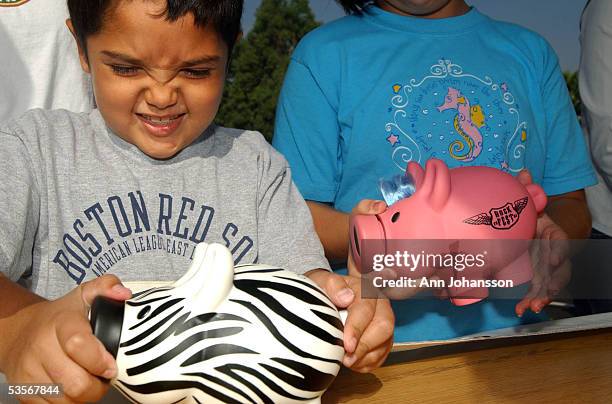 Michael Khatchadourina tries to open his piggy bank as he and his sister Krysta make a donation for victims of Hurricane Katrina at a daylong...