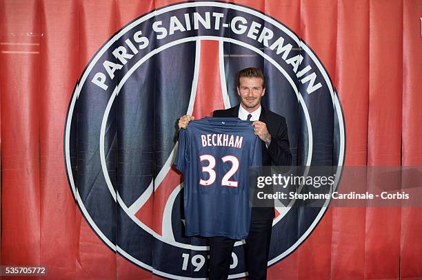 International soccer player David Beckham poses with his PSG Football shirt after his PSG signature at Parc des Princes, in Paris.