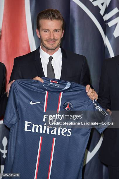 International soccer player David Beckham poses with his PSG Football shirt after his PSG signature at Parc des Princes, in Paris.