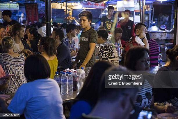 An employee, center, takes an order from a table of customers at a restaurant in the North Gate market in Chiang Mai, Thailand, on Sunday, May 29,...
