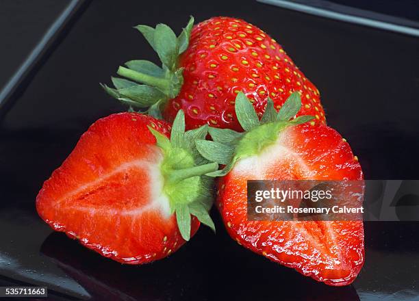 fresh strawberries on a black plate - half complete stock pictures, royalty-free photos & images