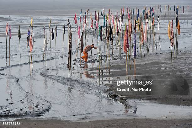 Dadang Christianto, an Indonesian artisan sets up an art installation titled Gombal known as rags at mudflow area during the tenth anniversary of the...