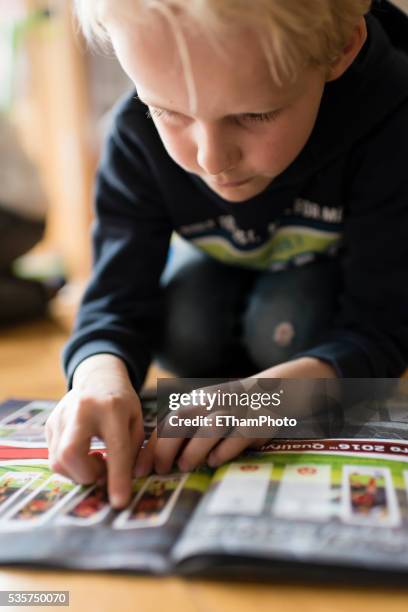 8 year old boy pasting soccer trading cards into his scrapbook - trading card stockfoto's en -beelden