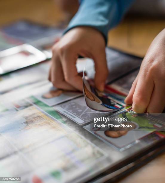 8 year old boy pasting soccer trading cards into his scrapbook - trading card stockfoto's en -beelden