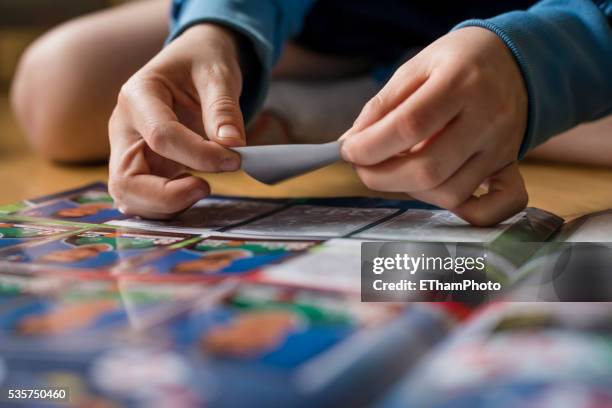 8 year old boy pasting soccer trading cards into his scrapbook - trading card stockfoto's en -beelden