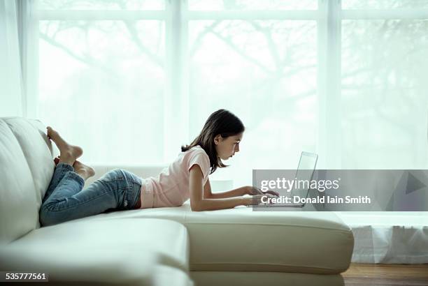 girl using laptop computer - barefoot feet up lying down girl stockfoto's en -beelden