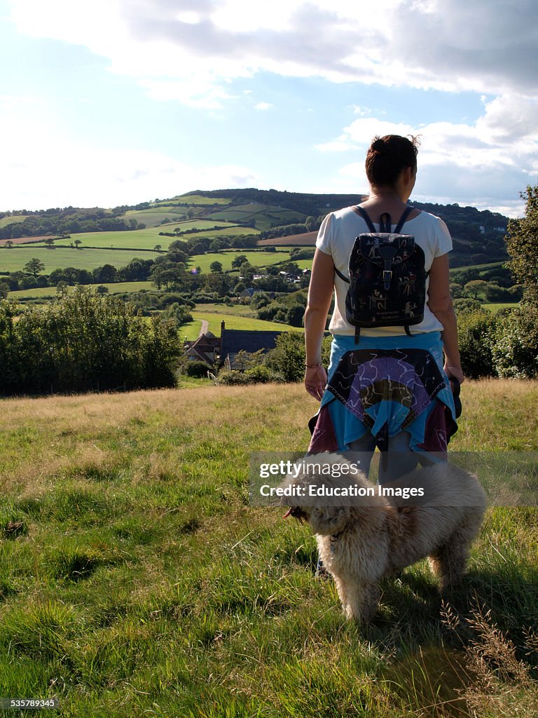 Woman with dog looking at view of Dorset countryside, Chideock, Dorset