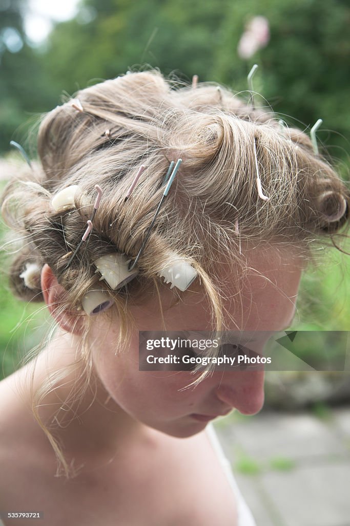 Portrait of young teenage girl with curlers in her hair looking down thoughtfully