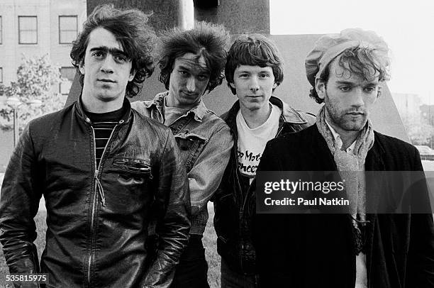 Portrait of the band REM posing outdoors next to a sculpture at Park West, Chicago, Illinois, May 26, 1983.