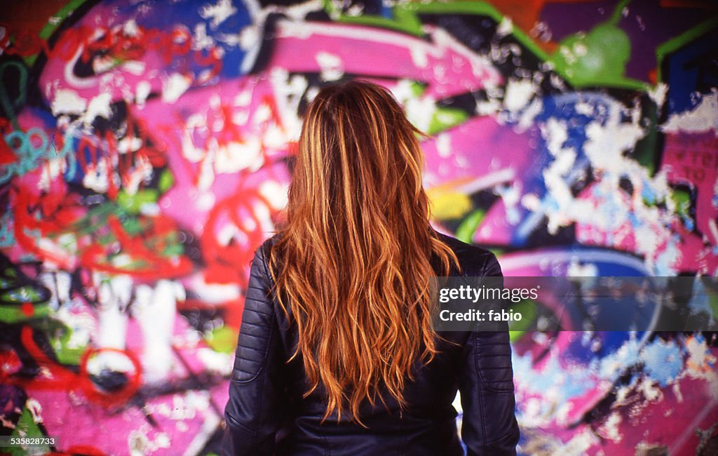 France, Rear view of young woman in front of colorful mural