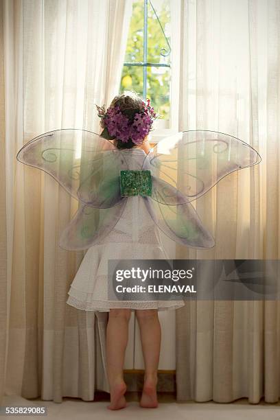 girl wearing fairy costume looking out of window - feenkostüm stock-fotos und bilder