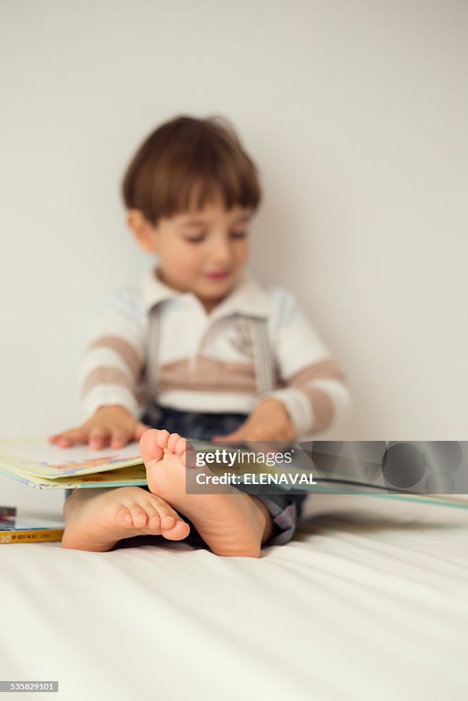 Boy sitting on his bed reading a book