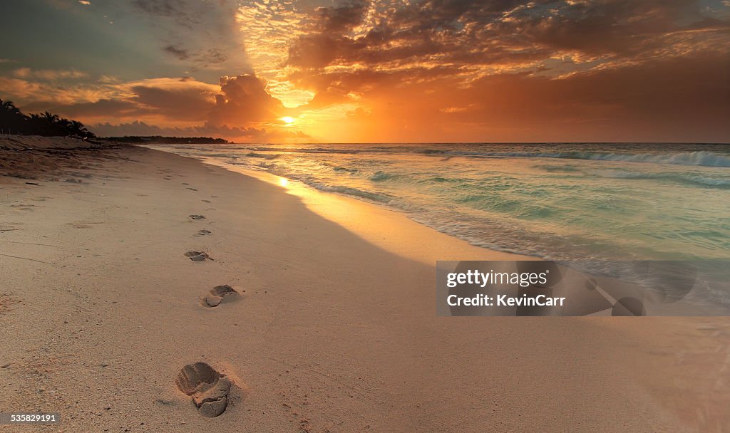 Mexico, Riviera Maya, Akumal beach, View along coastline with footprints in sand at sunrise