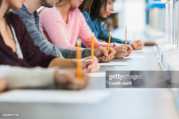 vista ritagliata di gruppo di adolescenti prendendo un test - student high school foto e immagini stock