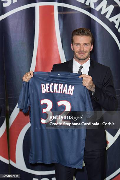 International soccer player David Beckham poses with his PSG Football shirt after his PSG signature at Parc des Princes, in Paris.